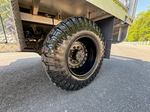 Front wheel and tire close-up with fender flare and side step visible.